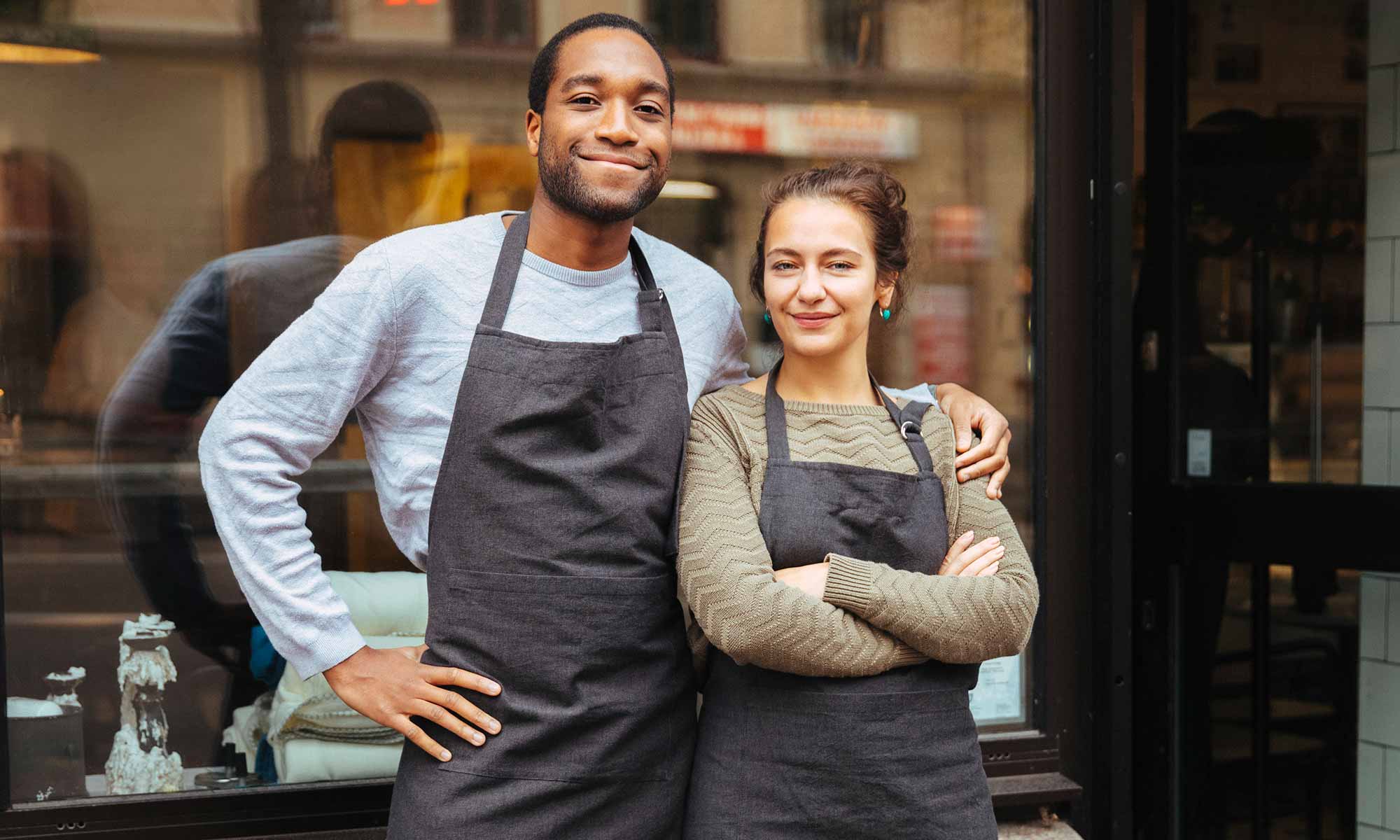 Två glada caféägare utanför sitt café