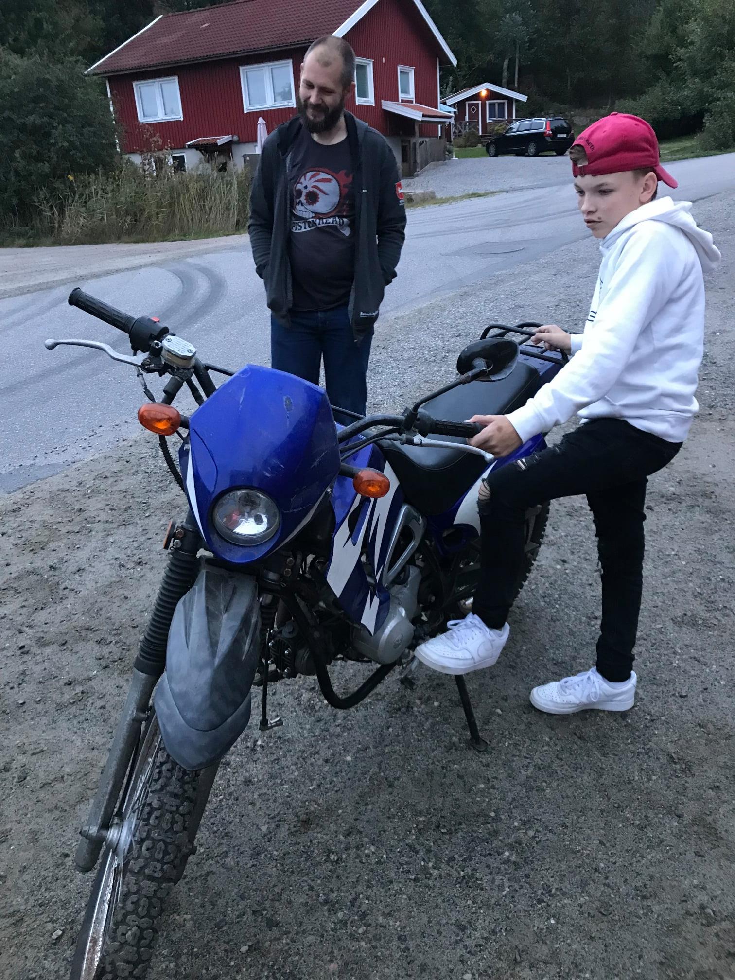 Två killar står vid en blå motorcross