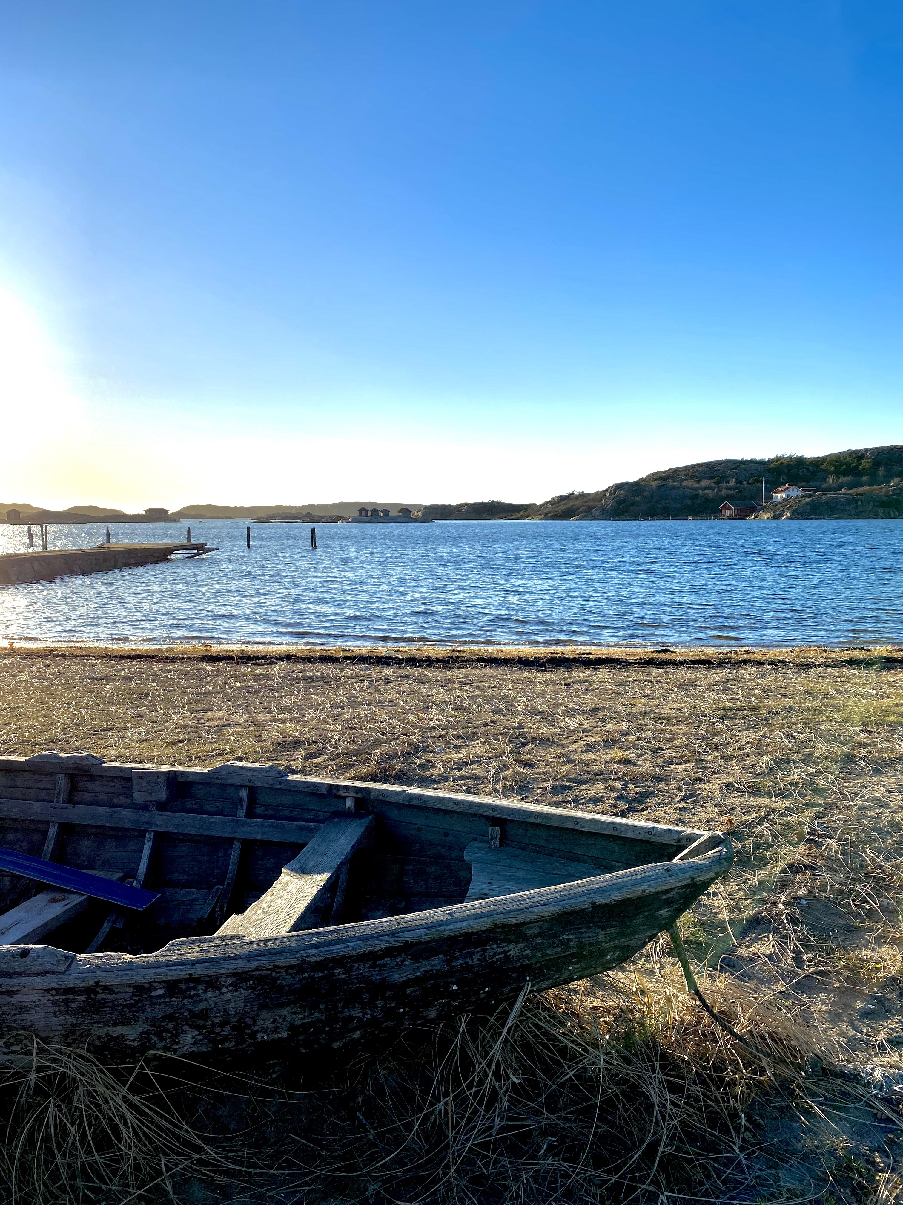 En träeka ligger på en strand vid havet i Grönemad