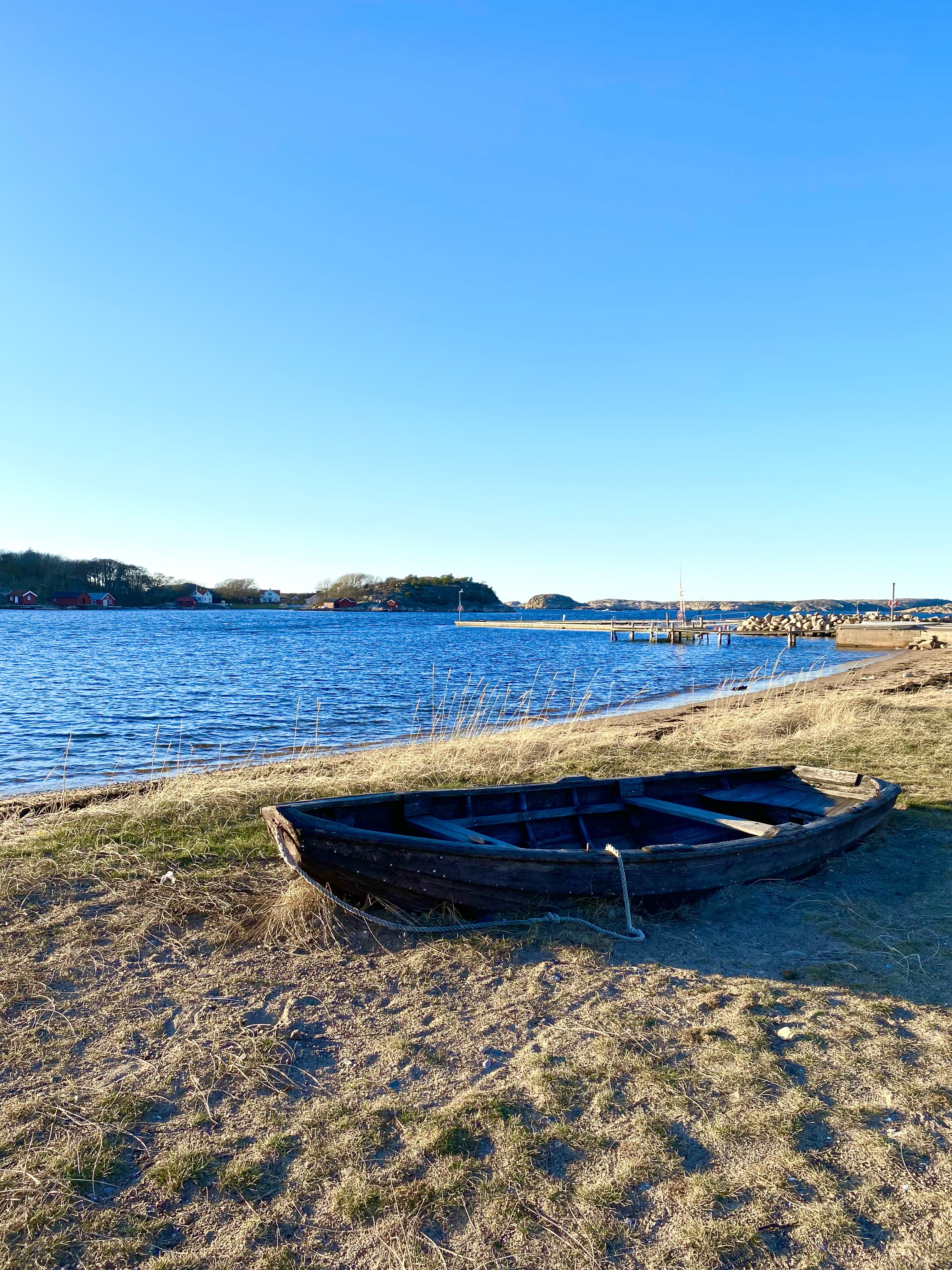 En träeka ligger på en strand vid havet i Grönemad