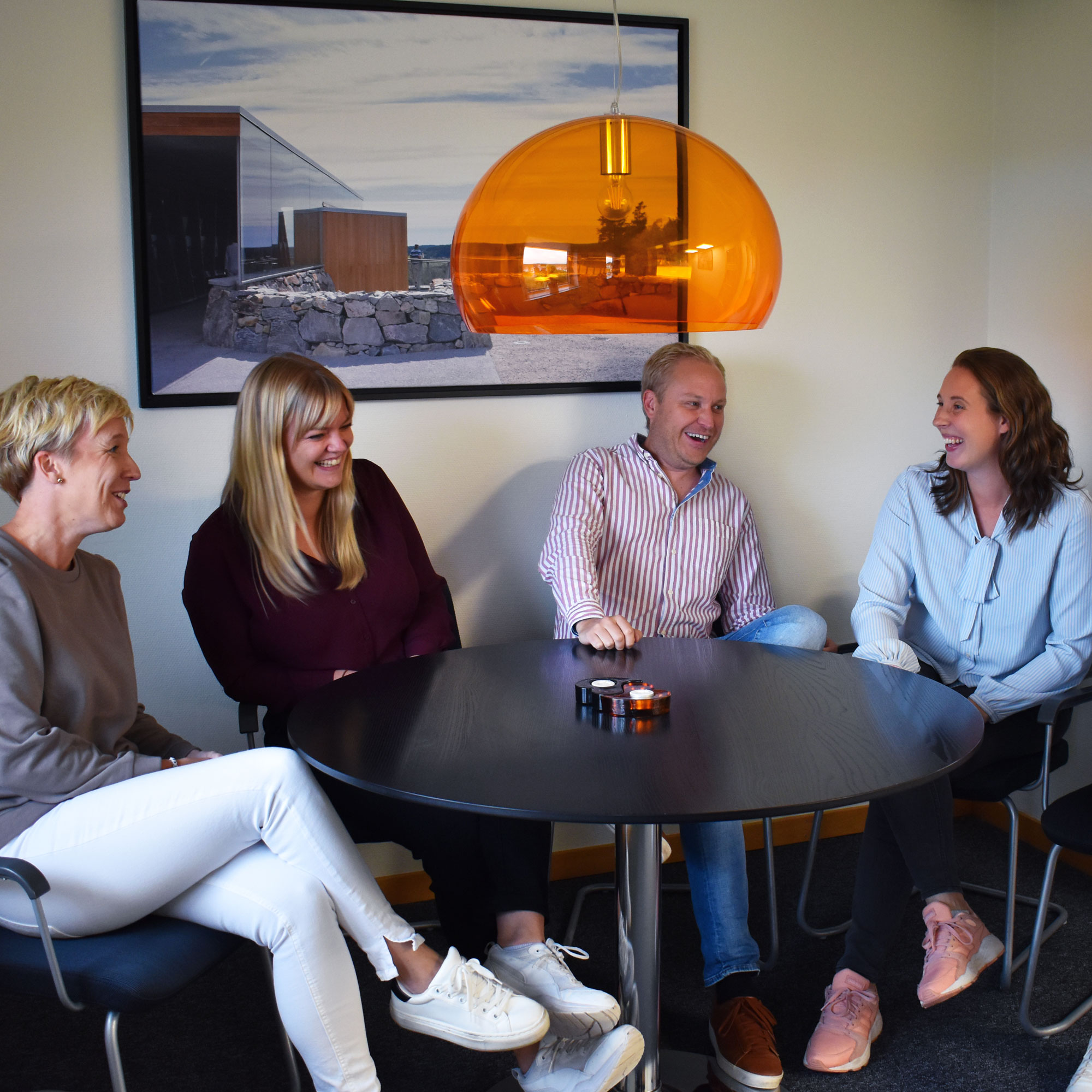 Personal på Sparbanken Tanum sitter runt ett bord och pratar och skrattar